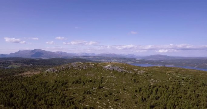 Left slide aerial drone shot from Golsfjellet, a mountain located in Hallingdal, Norway. Small peak in the foreground of the frame.
