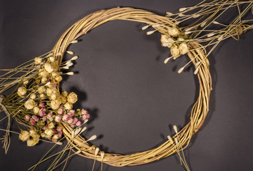 Wreath of twigs and dried flowers on a dark background.