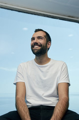 Handsome man smiling on the deck of a ship during holidays.