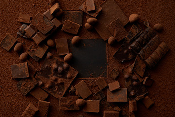 top view of chocolate pieces with nuts and cocoa powder on dark background