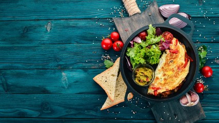 Omelet with vegetables and mushrooms in a frying pan. On a wooden background. Free space for text....