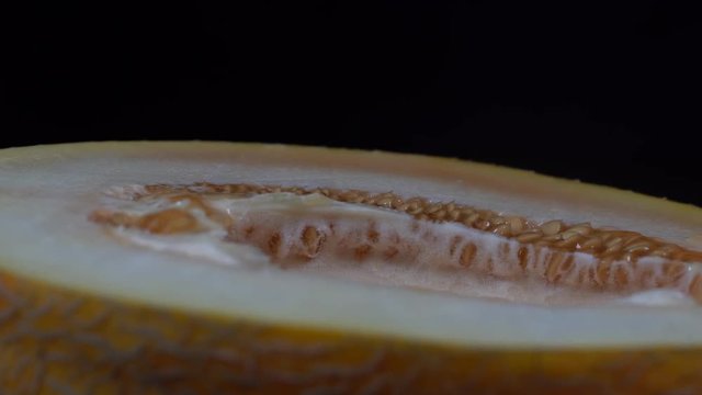 Yellow melon on a black background, close up. Rotates half yellow melon, macro