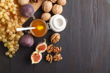 honey jar with a spoon for honey and nuts on a dark background