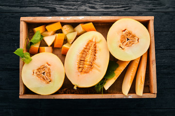 Melon in a wooden box. Sliced to pieces of melon. On a wooden background. Free space for text. Top view.