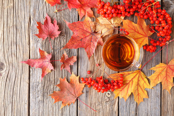 Cup of linden tea with autumn leaves on a wooden background