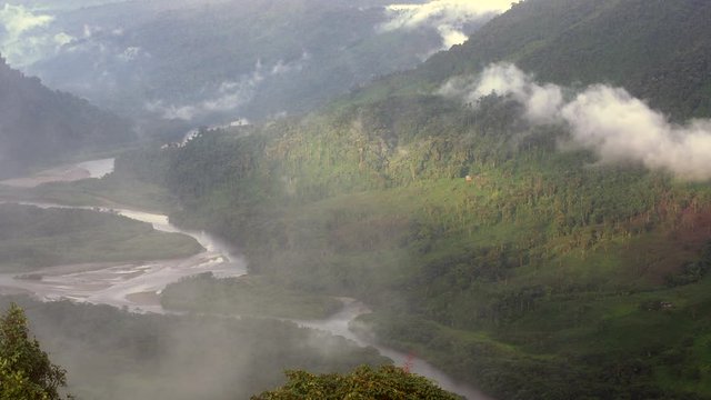 The Rio Abanico Valley, Ecuador, with misty cloudforest covered hillsides. Farmsteads cleared from forest illuminated by evening sun.  On the Amazonian slopes of the Andes in Morona Santiago province