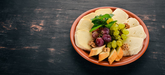 Cheese on a plate. Brynza and Suluguni cheese. On the old wooden background. Free space for text. Top view.