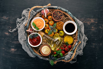 Set the sauces on a black wooden background. Ketchup, mayonnaise, mustard, soy sauce, barbecue sauce, pepper and spices. Top view. Free space for text.