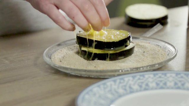 Slo motion shot 400fps of an aubergine burger filled with cheese coated in breadcrumbs filmed in a clean and tidy middle class kitchen.