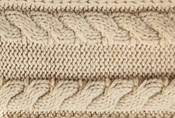 Close up of beige knitted winter sweater with pattern as textured material concept.