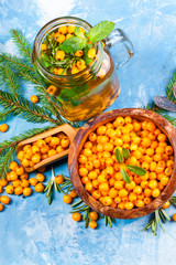 Sea buckthorn berries on wooden bowl on bright background