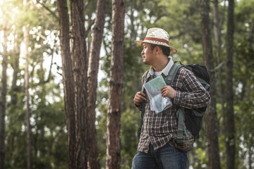Male hiker with backpack holding map in the forest