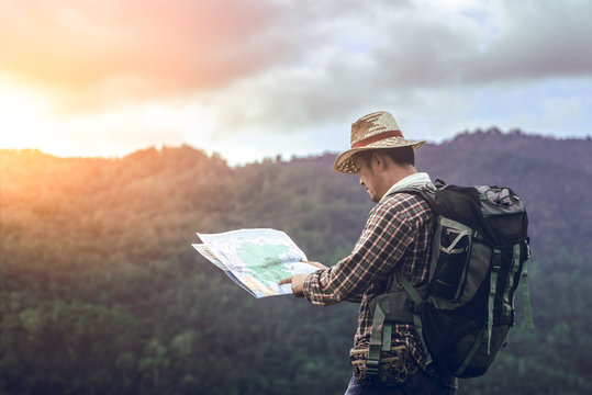 hiker with backpack standing holding map looking for checking on the mountain