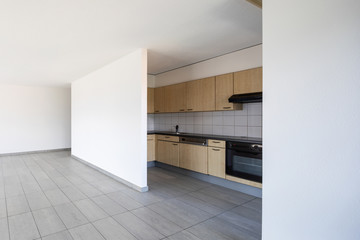 Empty room with windows and wooden kitchen
