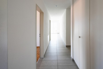Corridor with tiles, fitted wardrobes and open doors