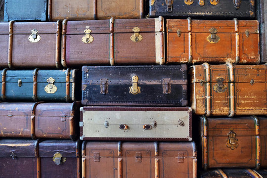 Texture of vintage suitcases one above the other of the 90s, suitcases of different colors and materials, in fabric, in leather. Concept of: memories, past, vintage.