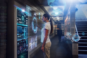 In a subway, a woman clicks on a futuristic digital platform and features futuristic graphics that can help her on her journey. Concept of: future, technology, urban