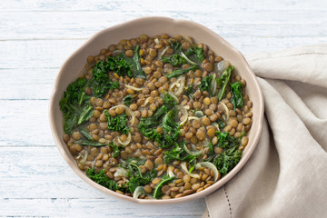 Stewed kale lentils with onions and garlic on a light background, selective focus. Delicious homemade healthy food