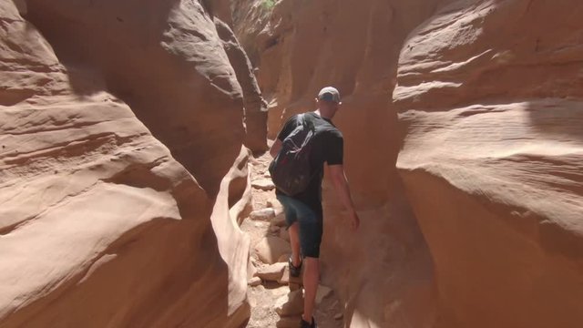 A man picks his way through a slot canyon in southern Utah.