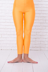 first ballet position of female feet in orange tights. leg of dancer in first position. dance class...