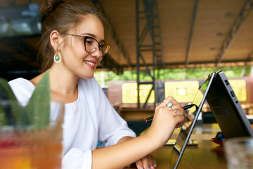 Freelancer mixed race woman hand pointing with stylus on convertible laptop screen in tent mode....
