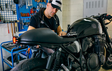 Mechanic checking motorcycle and taking notes