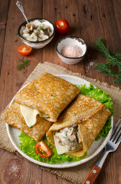 Pancakes stuffed with mushrooms and cheese with cream sauce