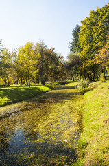 Beautiful autumn park with colorful trees and leaves and reflection in artificial ponds.