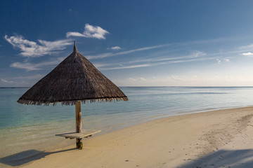 Umbrella on white sand at tropical Olhuveli island, south Male Atoll, Maldives.