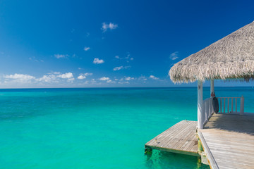 Beautiful beach with water bungalows and long jetty at Maldives. Summer travel holiday concept.