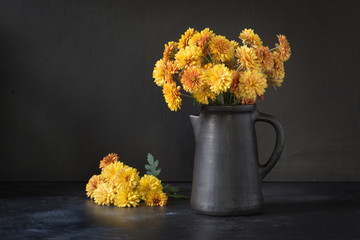 Autumn dark still life. Fall with yellow chrysanthemum flowers in clayware vase on black. © svetlana_cherruty