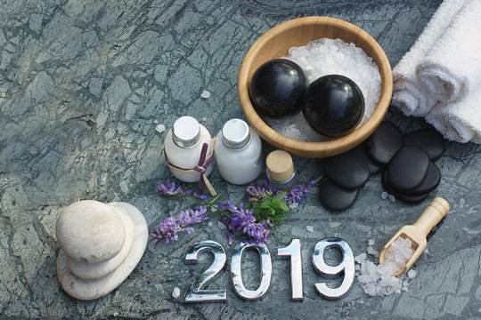 Set for spa treatments in 2019 on marble stone with candles, figures, bath salt and towels, copy space for your text