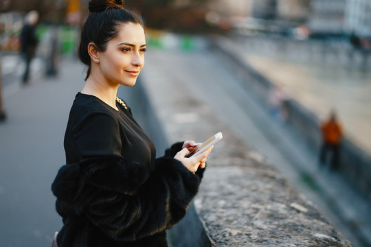 woman using her cell phone while walking through Paris