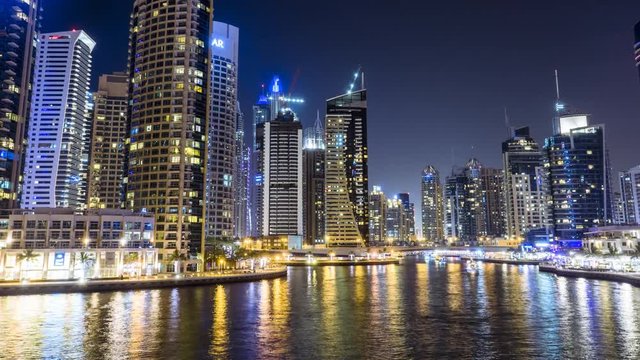 Night timelapse of Dubai Marina with skyscrapers and party boats in the canals