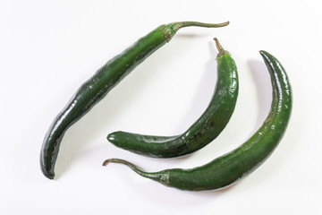 Top angled view of three green chilaca peppers isolated on white, horizontal aspect