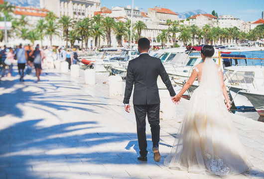 The bride and groom are walking along the embankment of the city Split.
