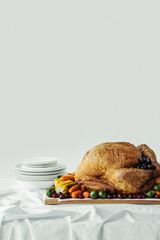 close up view of holiday dinner table set with roasted turkey and vegetables on grey background, thanksgiving holiday concept