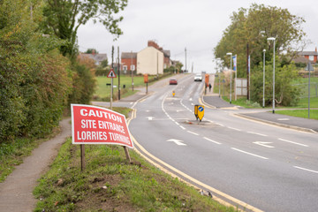 Caution site entrance lorries turning warning road sign on British road daylight view