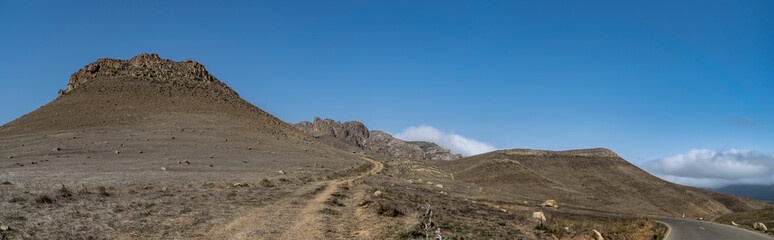 Fototapeta na wymiar Trekking path in the mountains with a view of high rocks and blue sky. Talysh Mountains. Azerbaijan, Yardymli. mountainous road