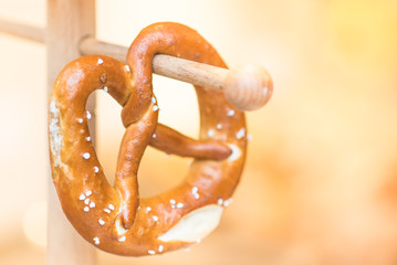 Fresh Pretzel hanging background. Twisted-knot shaped crusty white bread roll traditionally served with beer on famous German Oktoberfest in Munich, is popular in many European countries and USA