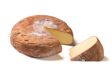 Top view of cheese wheel and slice on white.