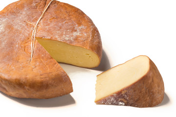 Top view of cheese wheel and slice on white.