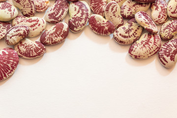 Obraz na płótnie Canvas Background arch of red speckled October beans on white, creative copy space, horizontal aspect