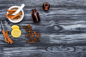 top view of bottles of natural herbal essential oils, cinnamon sticks and carnation on wooden table