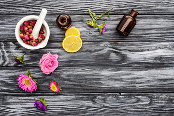 top view of bottles of natural herbal essential oils, flowers and pestle with mortar on wooden table