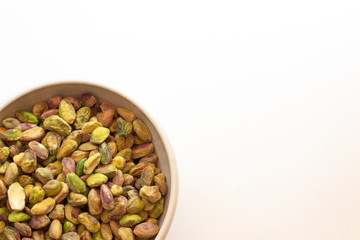 Ceramic bowl of salted, shelled pistachio nuts, copy space, isolated on white, horizontal aspect