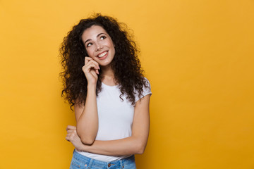 Image of gorgeous woman 20s with curly hair smiling and looking upward, isolated over yellow...