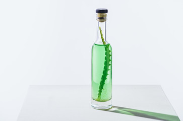 transparent bottle of natural herbal essential oil with aloe vera on white cube