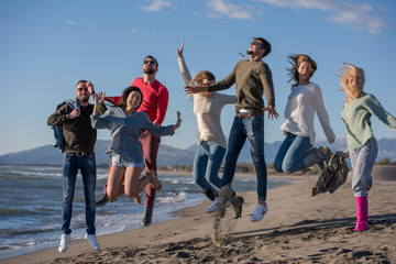 Obraz premium young friends jumping together at autumn beach