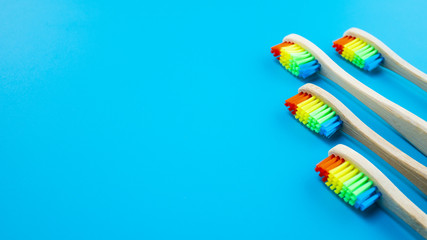 Rainbow bamboo wooden toothbrushes on blue background. Concept of racism, social exclusion, depression or loneliness, social problems or illegal migration